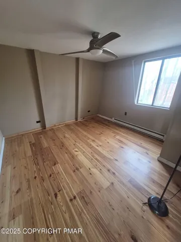 a view of empty room with wooden floor and fan