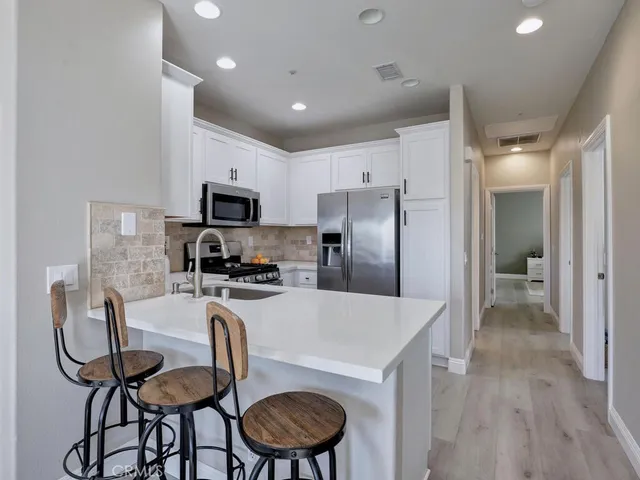 a kitchen with granite countertop a table chairs refrigerator and microwave