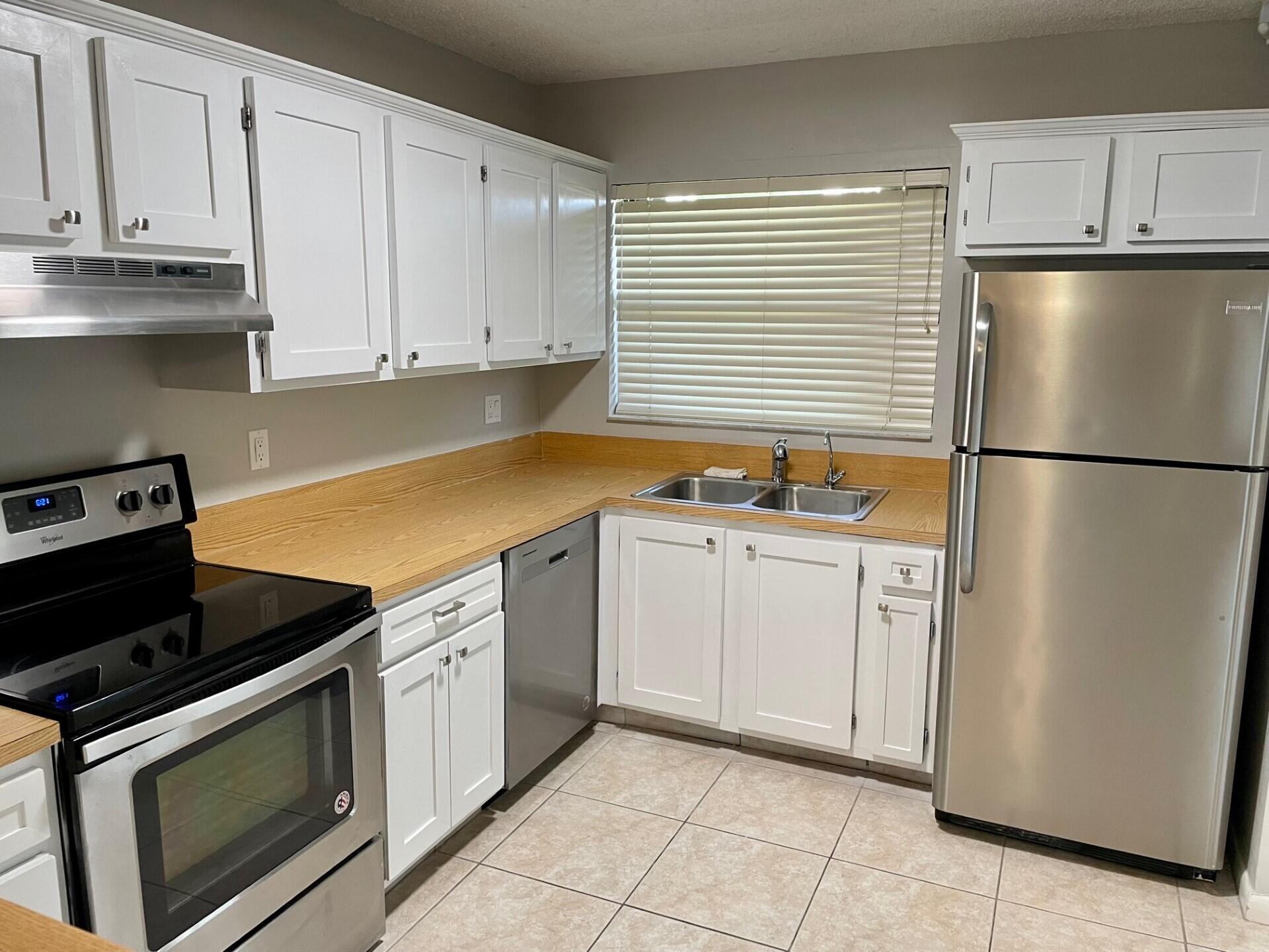 1271 Southeast Parkview Place, Unit H4 Stuart, FL 34994 - Photo 6 of 15 a kitchen with white cabinets and white appliances