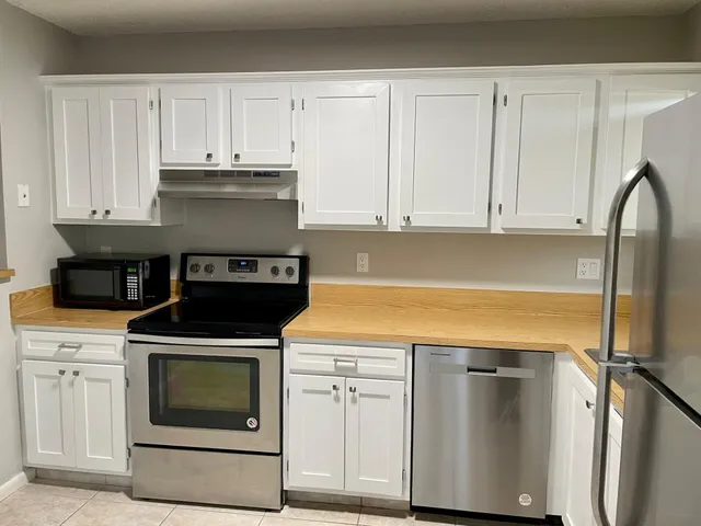 a kitchen with granite countertop white cabinets and stainless steel appliances