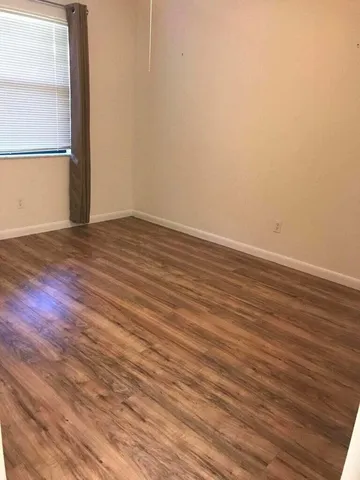 a view of an empty room with wooden floor and a window
