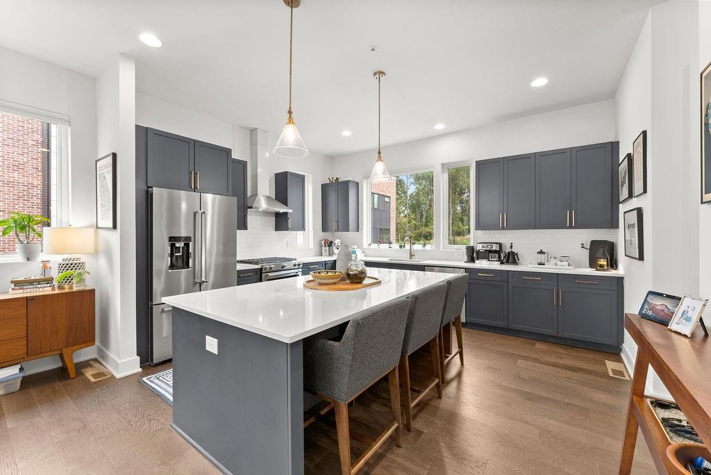 a large kitchen with a center island wooden floor stainless steel appliances and windows