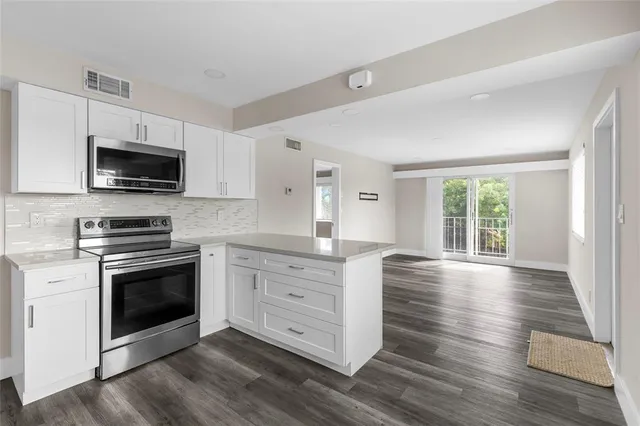 a kitchen with stainless steel appliances kitchen island granite countertop a stove a sink and a microwave