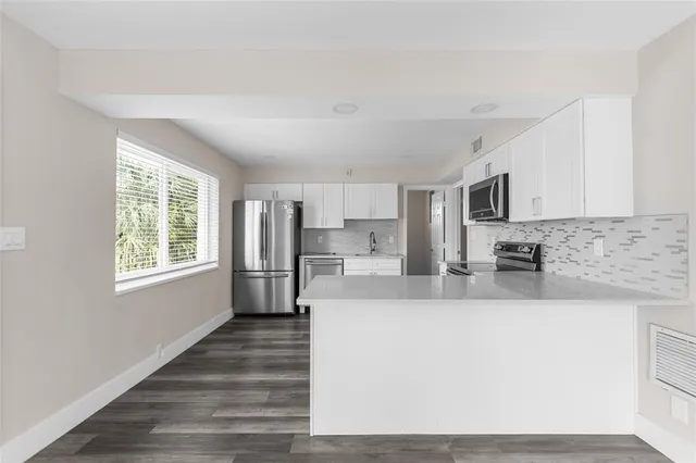 a large kitchen with stainless steel appliances granite countertop a stove a sink dishwasher and a refrigerator with wooden floor