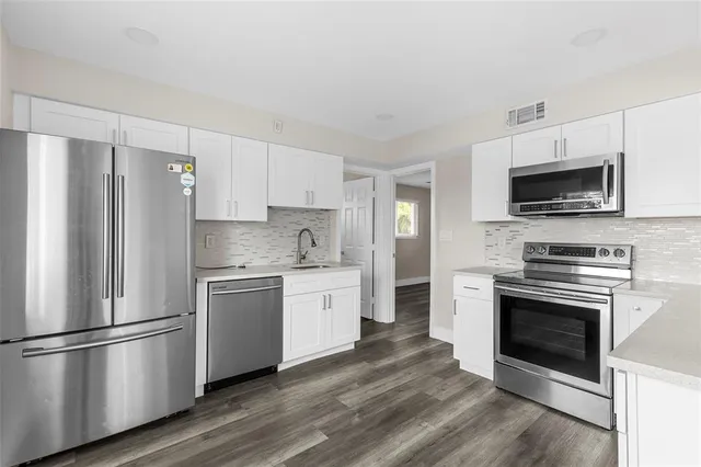 a kitchen with a refrigerator stove and white cabinets