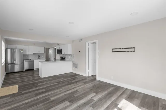 a view of a kitchen with cabinets stainless steel appliances wooden floor and a window