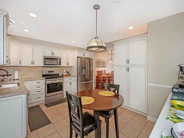 a kitchen with stainless steel appliances a dining table chairs stove refrigerator and microwave