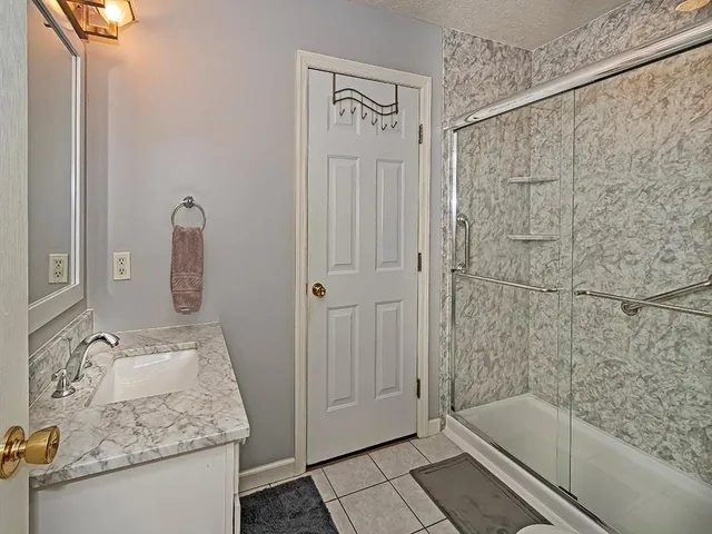 a bathroom with a granite countertop sink a mirror and shower