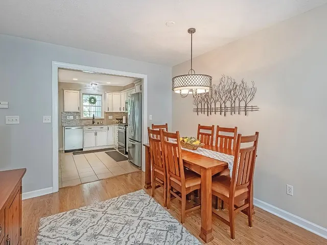 a view of a dining room and livingroom with furniture wooden floor a rug and a chandelier
