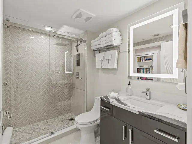 a bathroom with a granite countertop sink toilet a mirror and shower