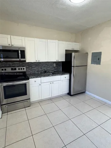 a kitchen with granite countertop a refrigerator and a stove top oven