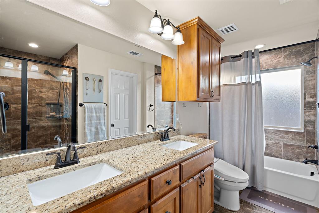 904 Sam Street Springtown, TX 76082 - Photo 16 of 30 a bathroom with a granite countertop sink a toilet a mirror and shower
