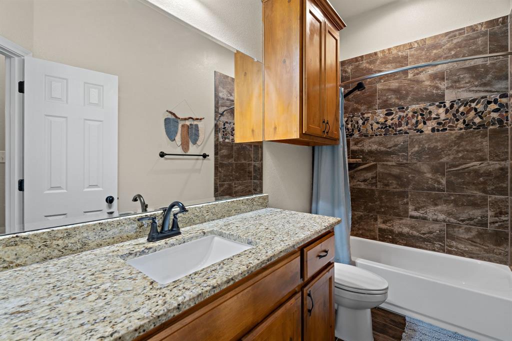 904 Sam Street Springtown, TX 76082 - Photo 18 of 30 a bathroom with a granite countertop sink toilet and shower