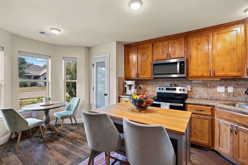 904 Sam Street Springtown, TX 76082 - Photo 9 of 30 a kitchen with a stove a sink a microwave a dining table and chairs
