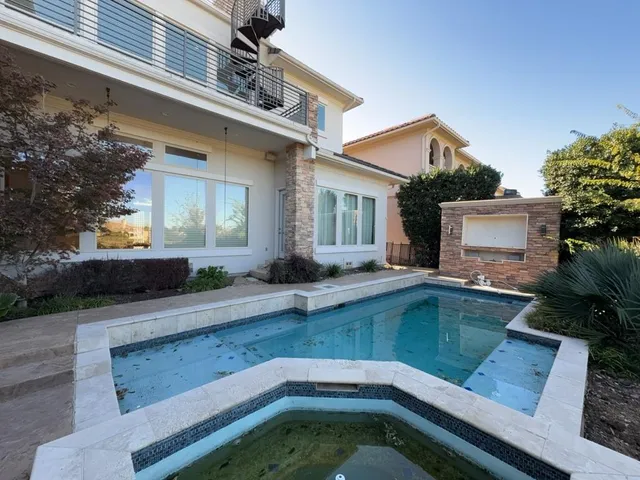 a view of a house with pool plants and wooden fence