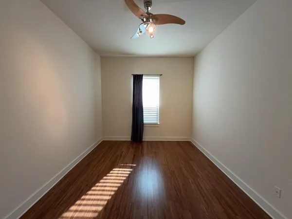 a view of an empty room with wooden floor and a window