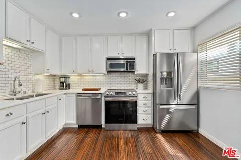 a kitchen with wooden floors and stainless steel appliances