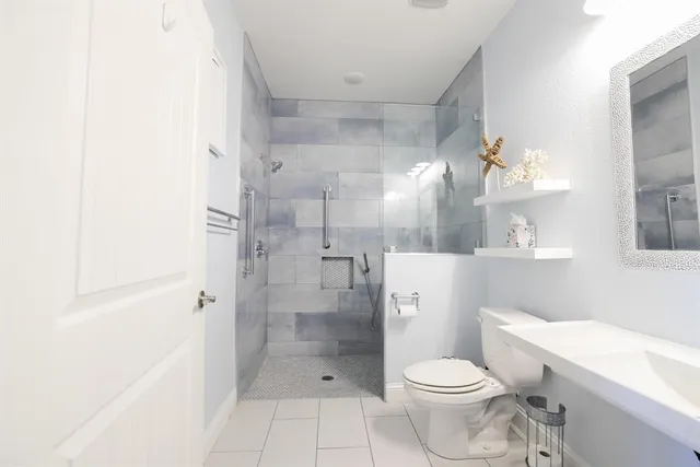 a bathroom with a granite countertop toilet a sink a shower and a mirror