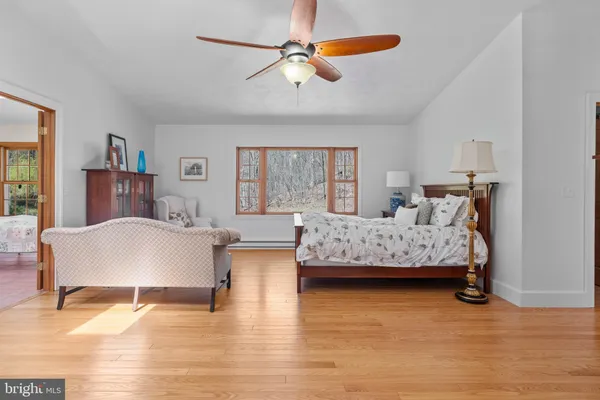 a bedroom with a bed couches chair and a large window