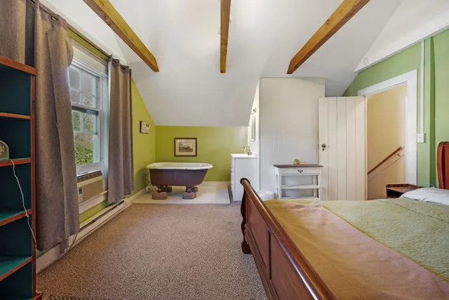 a spacious bedroom with a bed a dresser and a large window