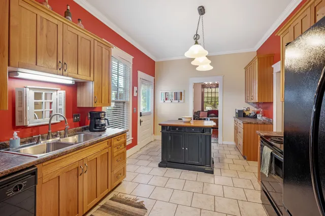 a large kitchen with granite countertop a stove a sink dishwasher and a refrigerator with wooden floor