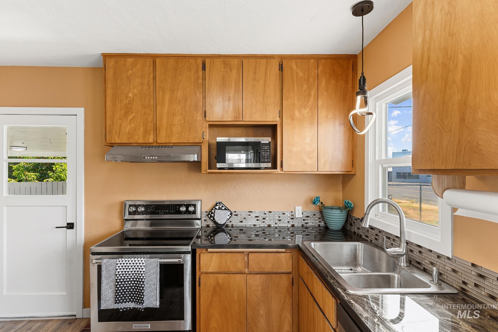 619 Thain Road Lewiston, ID 83501 - Photo 4 of 44 Kitchen featuring natural wood cabinetry, stainless steel appliances, dark stone countertops, a tile backsplash, and a double basin sink with a gooseneck faucet