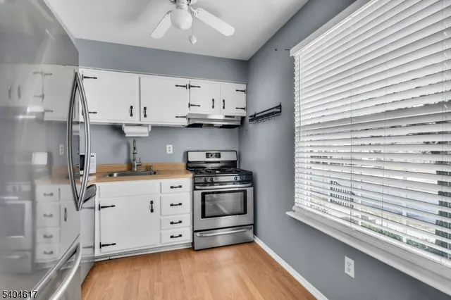 a kitchen with stainless steel appliances a stove a sink and white cabinets