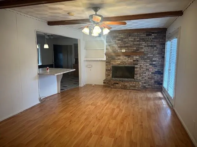 an empty room with wooden floor a fireplace and entryway