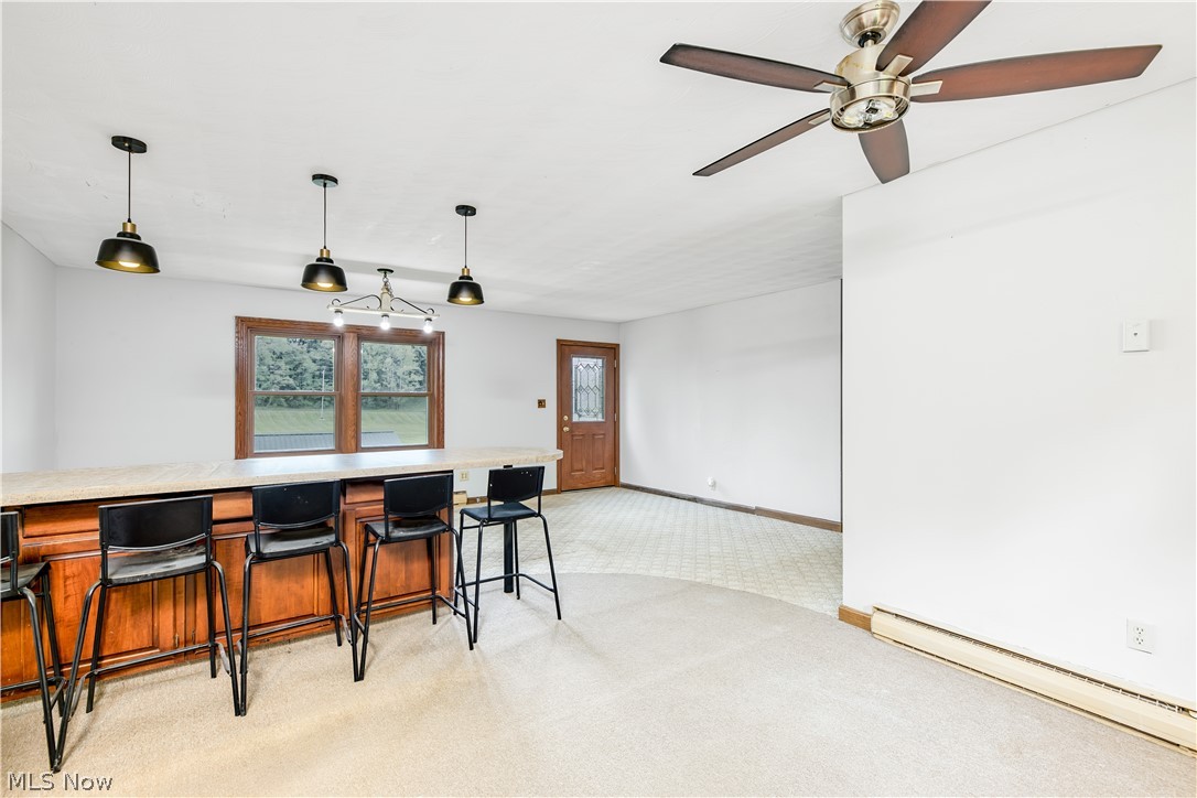 8750 Whitaker Road Cambridge, OH 43725 - Photo 12 of 29 Kitchen featuring a kitchen breakfast bar, ceiling fan, pendant lighting, light colored carpet, and baseboard heating