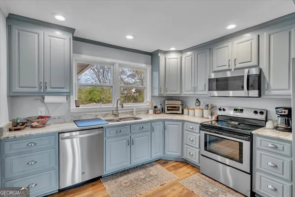 a kitchen with stainless steel appliances granite countertop a stove a sink and a microwave