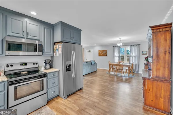 a kitchen with stainless steel appliances a stove a sink a refrigerator white cabinets and wooden floor