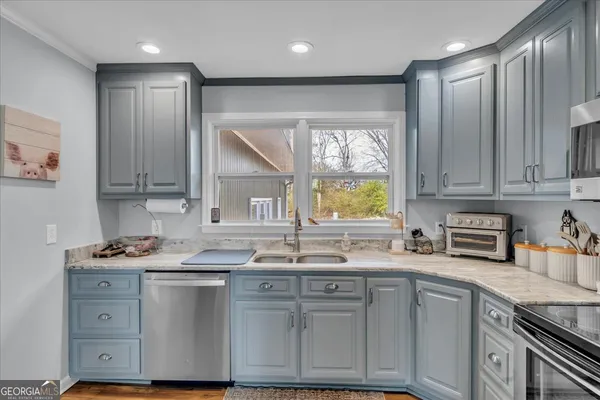 a kitchen with stainless steel appliances granite countertop a sink window and cabinets