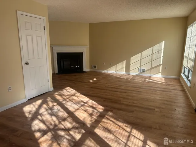 a view of an empty room with window and wooden floor