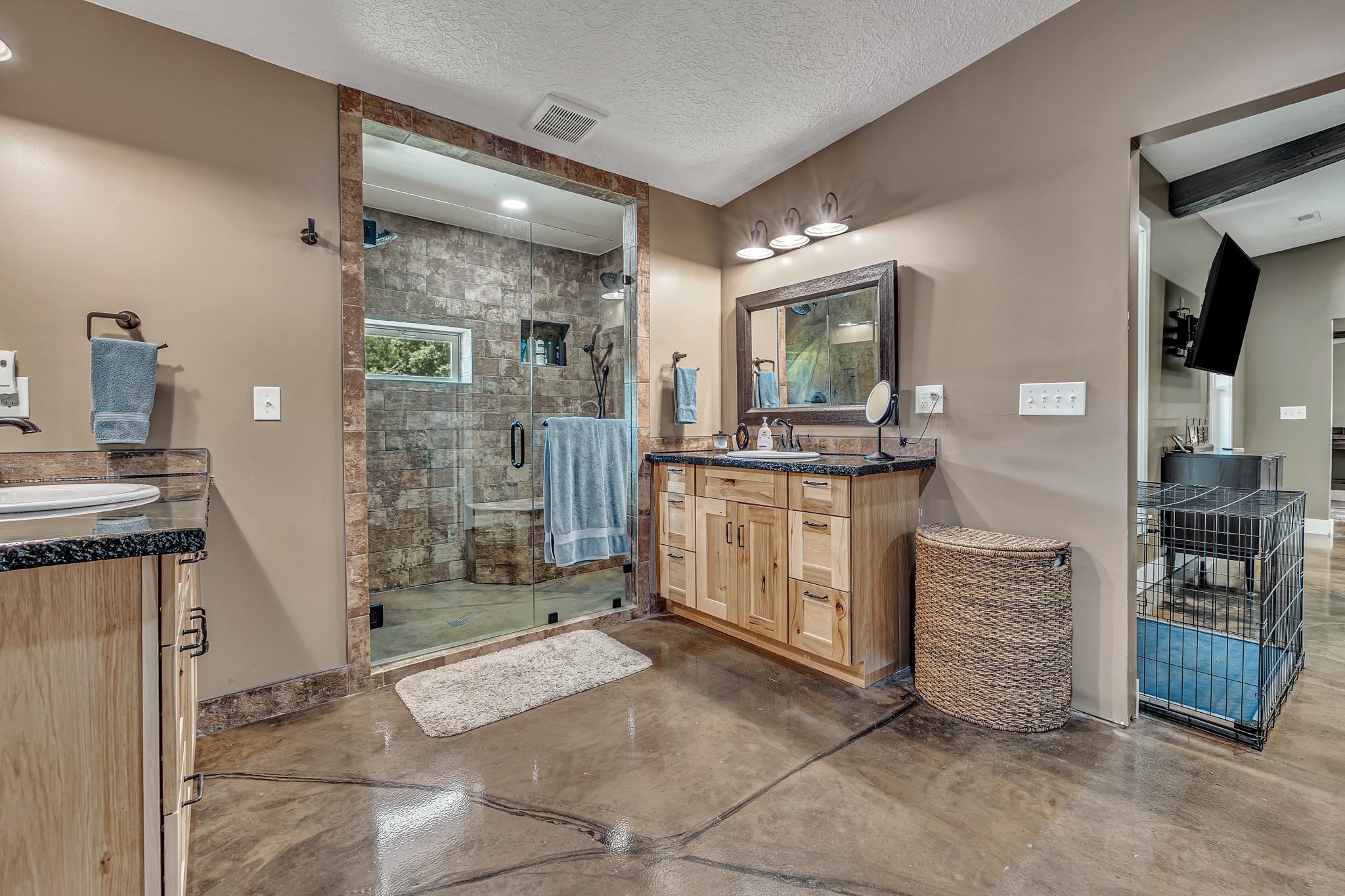 350 Hamilton Road Springville, TN 38256 - Photo 19 of 40 Spacious bathroom featuring a glass-enclosed shower with stone tile surround, a light wood-finish vanity with a dark countertop, and polished concrete flooring
