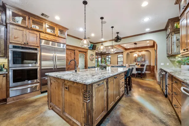 a kitchen with stainless steel appliances granite countertop a stove a sink a oven a dining table and chairs
