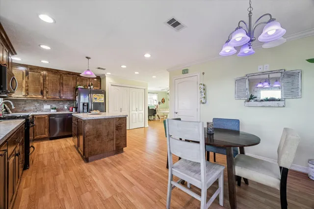 a kitchen with stainless steel appliances granite countertop a stove a sink dishwasher a refrigerator and a oven with wooden floor