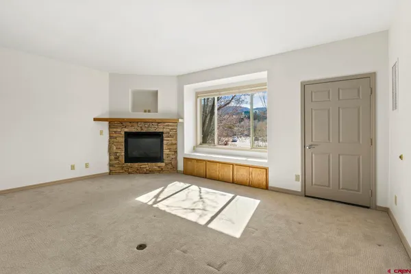 an empty room with windows and fireplace