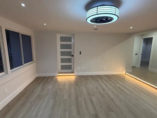 an empty room with wooden floor and windows