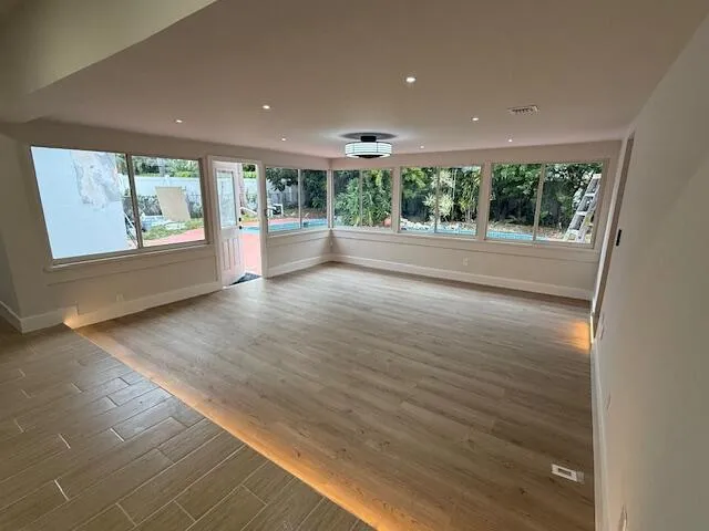 an empty room with wooden floor and outdoor view