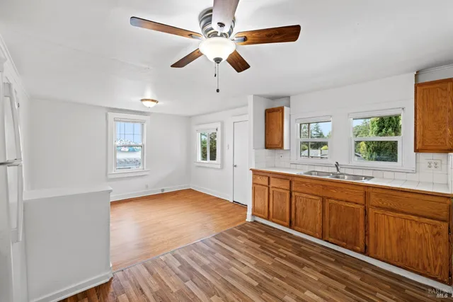 a view of a kitchen counter space with wooden floor and a ceiling fan
