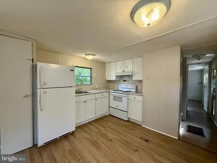 a kitchen with a refrigerator cabinets and wooden floor