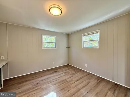 an empty room with wooden floor and window