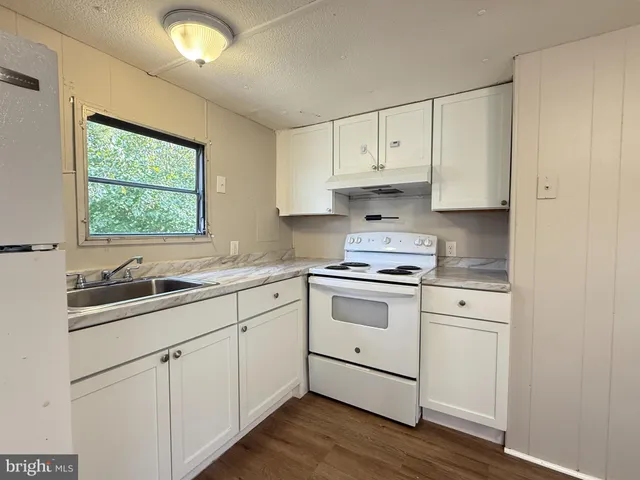 a kitchen with granite countertop white cabinets and white appliances