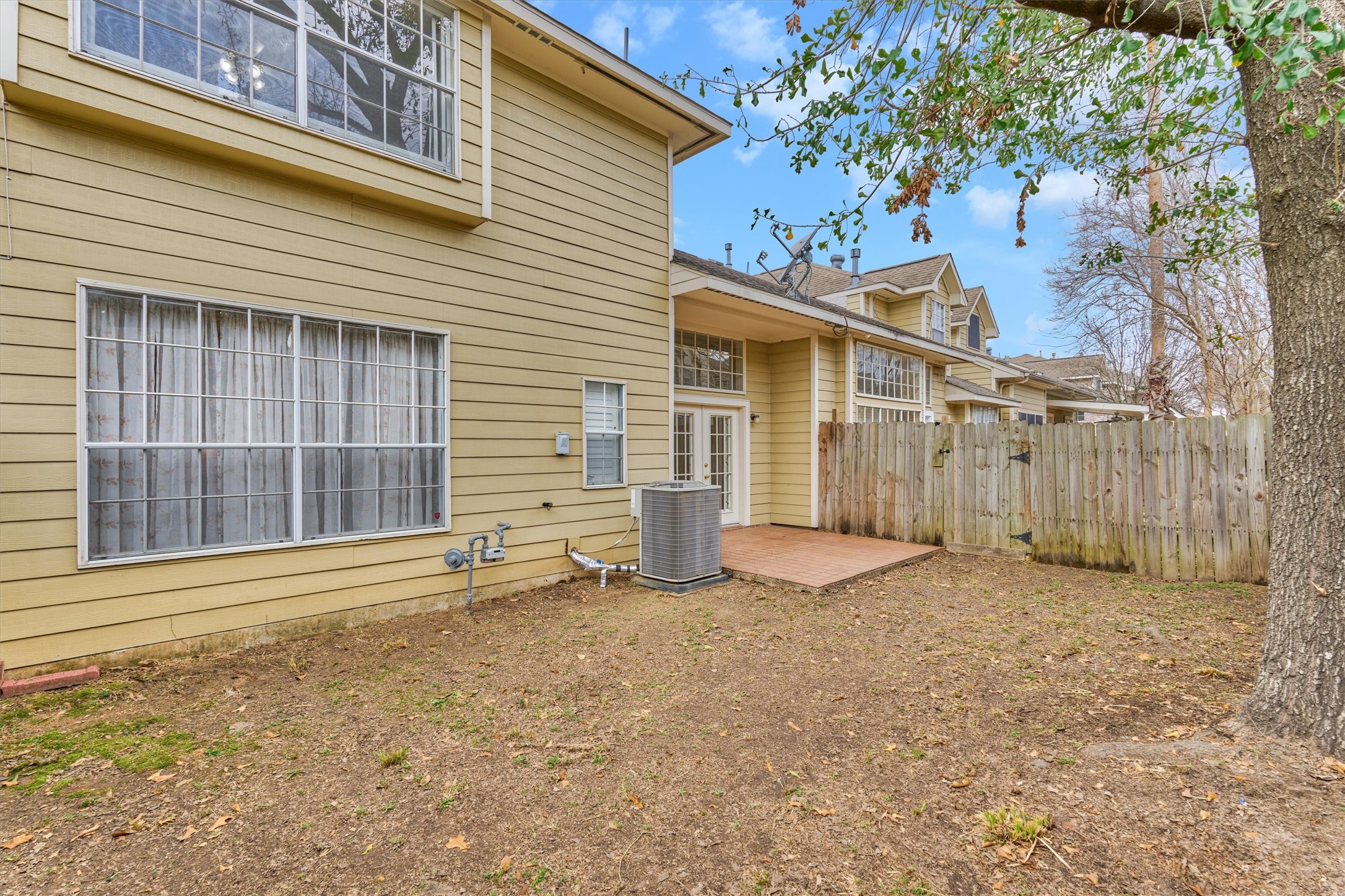 14420 Walters Road, Unit 26 Houston, TX 77014 - Photo 41 of 45 This photo shows the backyard featuring a modest patio area, large windows, and a fenced boundary, ideal for privacy and outdoor activities.