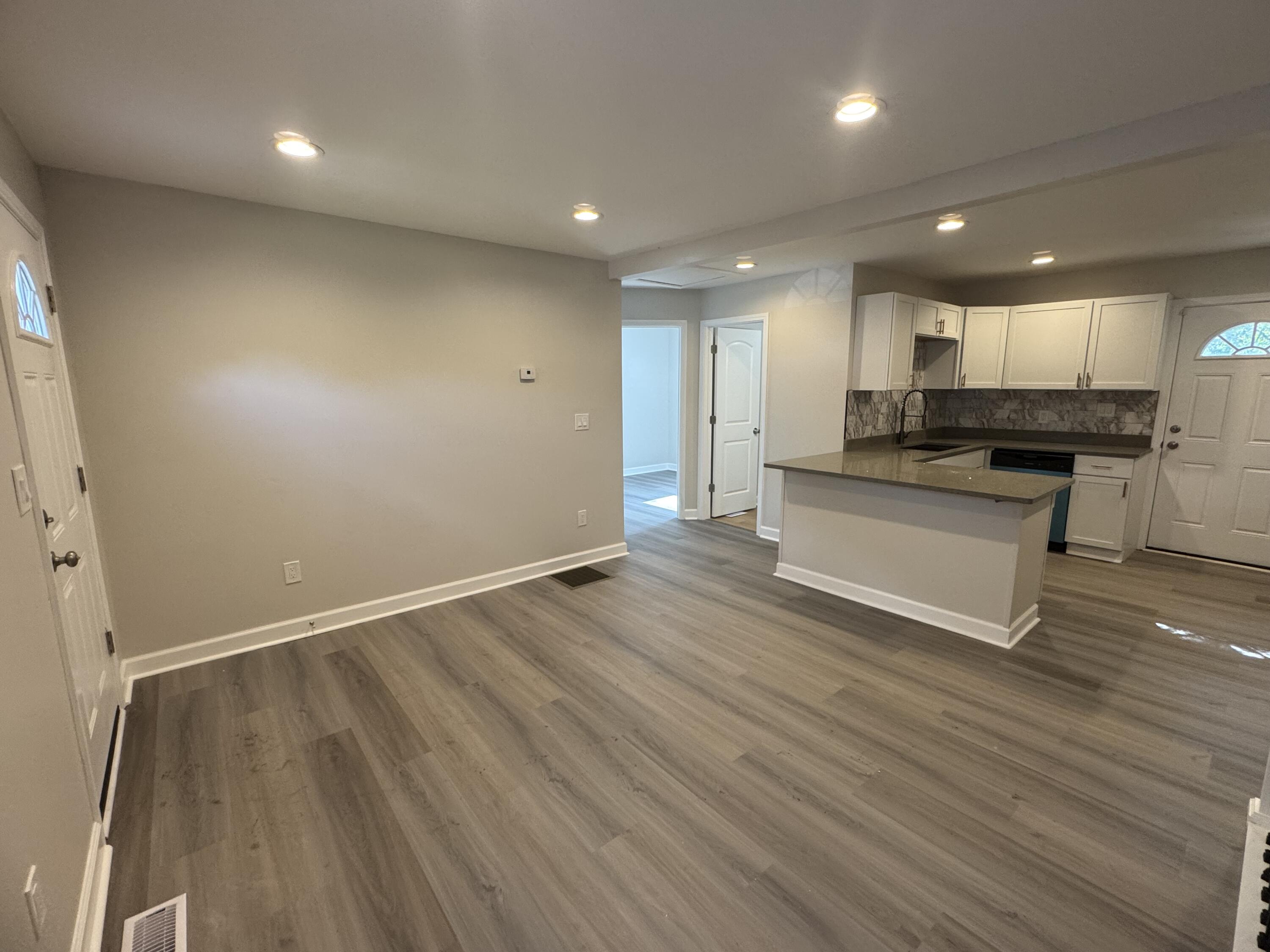 2344 Virginia Street Gary, IN 46407 - Photo 2 of 13 an empty room with wooden floor and kitchen view
