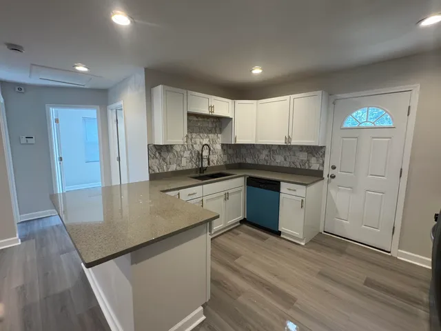 a kitchen with granite countertop a sink cabinets and wooden floor