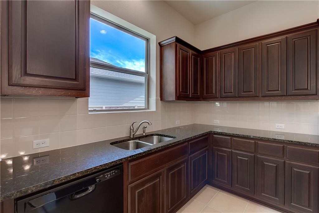 6907 Idea Road Austin, TX 78741 - Photo 9 of 29 Undermount kitchen sink with dark cabinets, granite counter tops, and window above sink