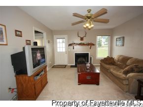 1890 Tingen Road Lillington, NC 27546 - Photo 3 of 12 a living room with furniture a fireplace and a flat screen tv