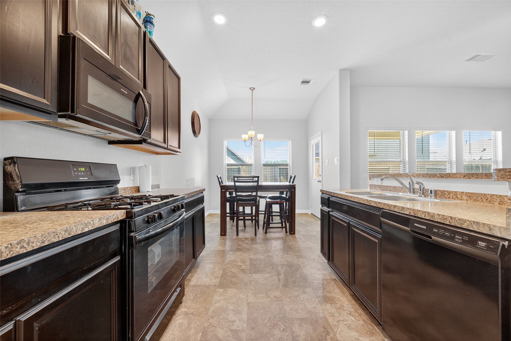 7615 Nevaeh Crest Path Houston, TX 77016 - Photo 16 of 37 a kitchen with stainless steel appliances granite countertop a stove top oven a sink dishwasher a dining table and chairs with wooden floor
