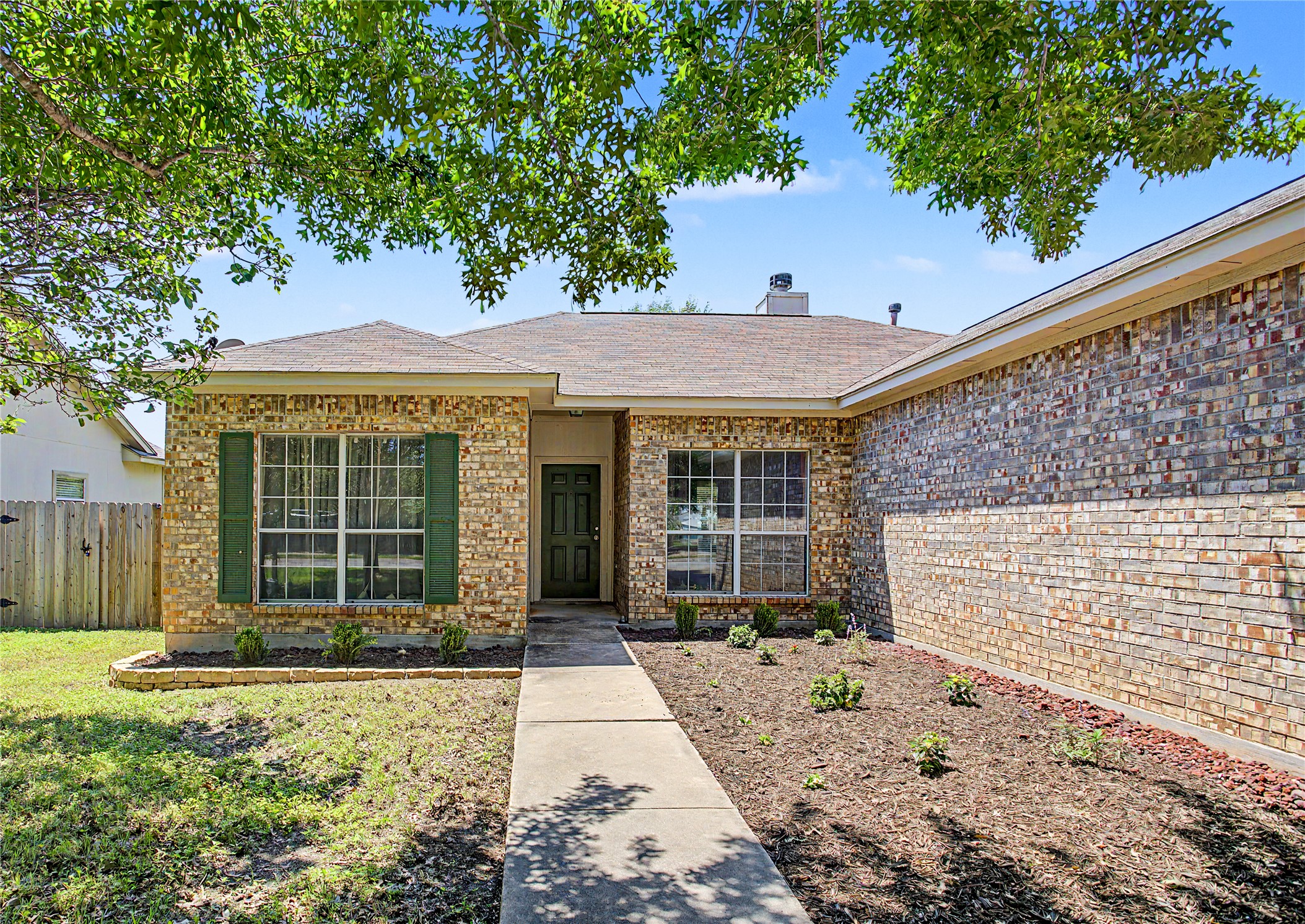 207 Kates Way Hutto, TX 78634 - Photo 13 of 24 Brick exterior featuring a gabled roof and green-shuttered windows